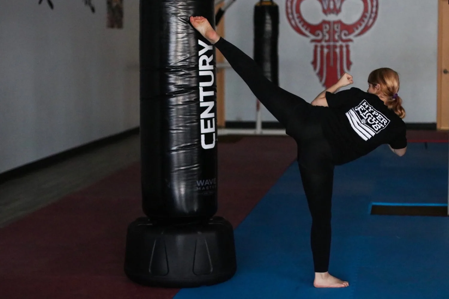 A martial artist practicing a high kick against a training bag
